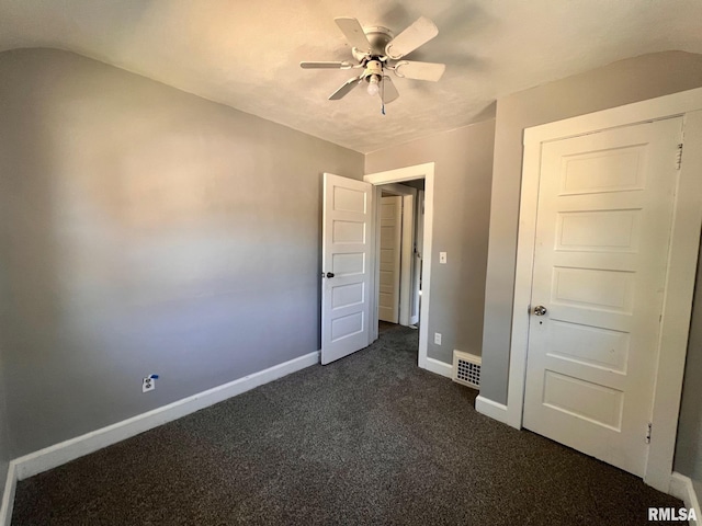 unfurnished bedroom with baseboards, visible vents, ceiling fan, vaulted ceiling, and dark colored carpet