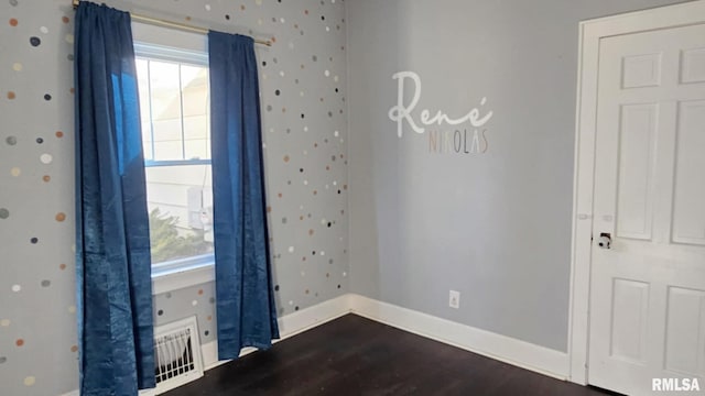 spare room featuring wallpapered walls, baseboards, dark wood-style flooring, and a wealth of natural light