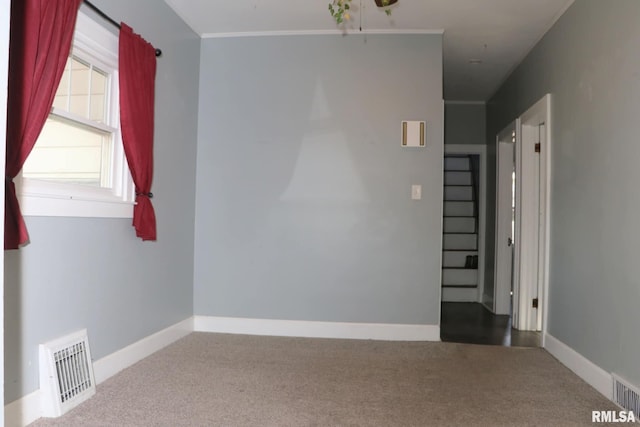 spare room featuring ornamental molding, carpet, visible vents, and baseboards