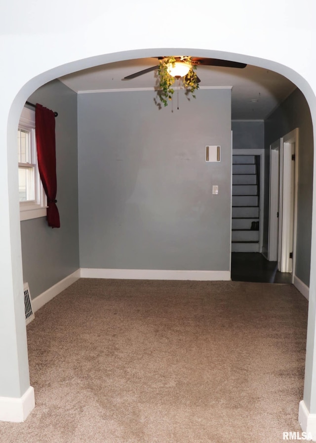 carpeted empty room featuring arched walkways, visible vents, stairway, and baseboards