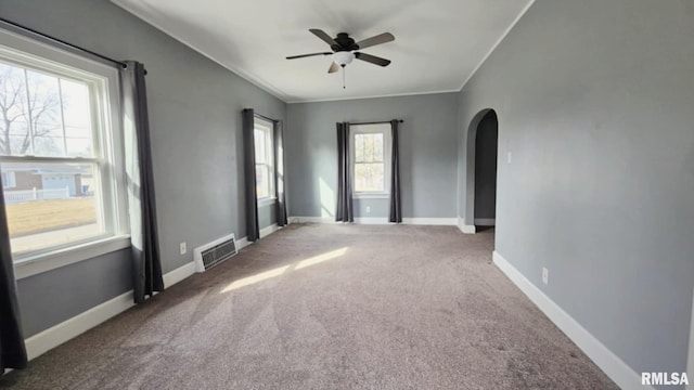 unfurnished room featuring baseboards, visible vents, arched walkways, carpet, and crown molding