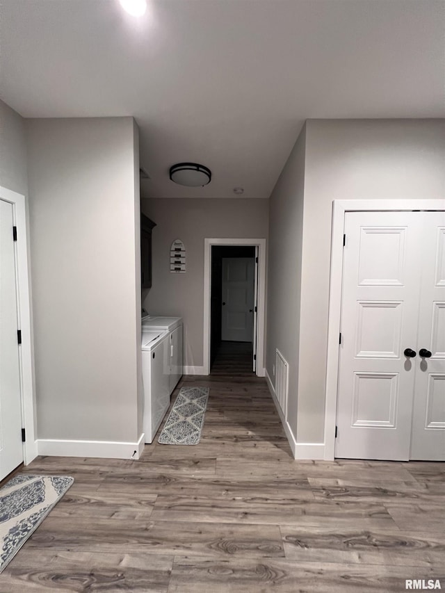 hall featuring light wood-type flooring, visible vents, baseboards, and washer and clothes dryer