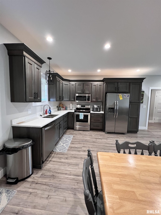 kitchen featuring appliances with stainless steel finishes, light countertops, pendant lighting, a sink, and recessed lighting