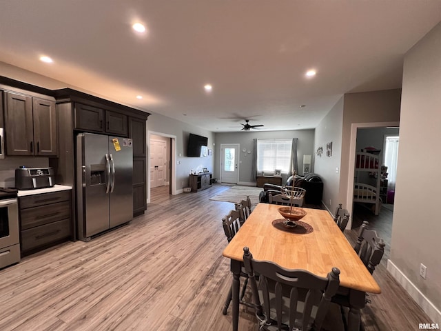 kitchen with dark brown cabinetry, light wood-style flooring, appliances with stainless steel finishes, open floor plan, and light countertops