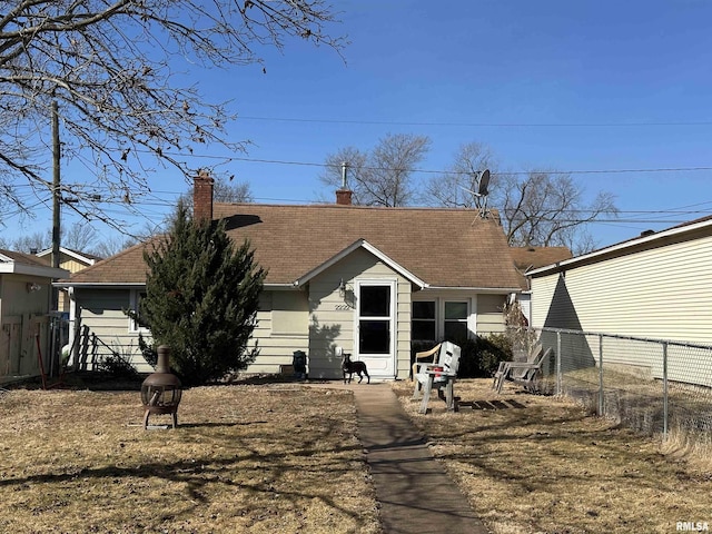 rear view of house featuring a shingled roof, an outdoor fire pit, fence, and a chimney