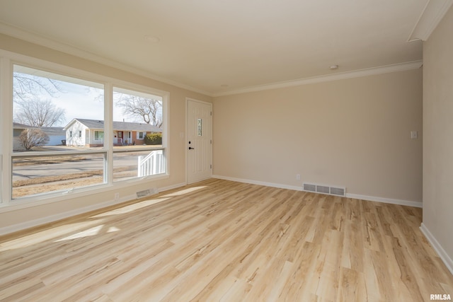 spare room featuring baseboards, light wood finished floors, visible vents, and crown molding