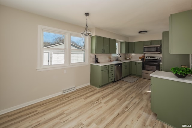 kitchen with visible vents, light wood-style floors, green cabinets, light countertops, and appliances with stainless steel finishes