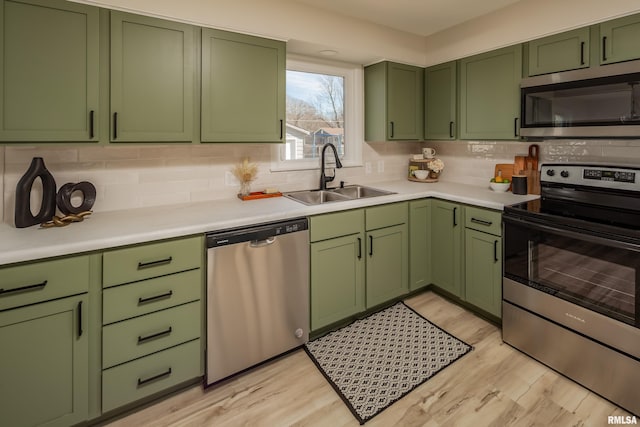 kitchen with stainless steel appliances, light countertops, a sink, and green cabinetry