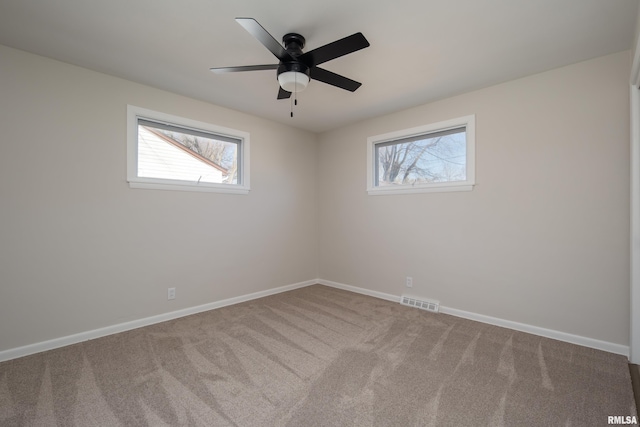 carpeted spare room featuring visible vents, ceiling fan, and baseboards