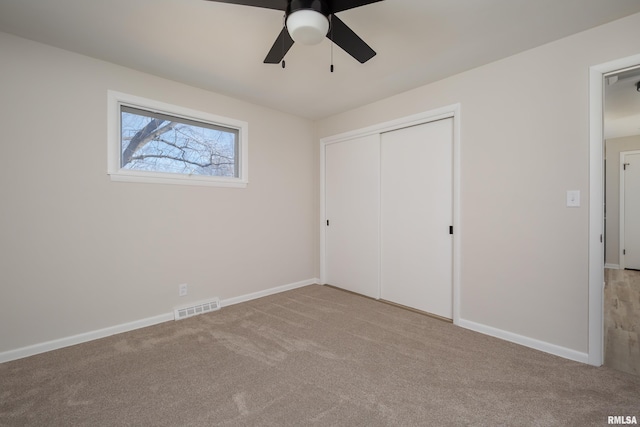 unfurnished bedroom featuring light carpet, baseboards, visible vents, and a closet