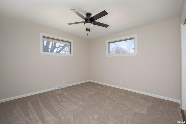 empty room with carpet floors, visible vents, ceiling fan, and baseboards