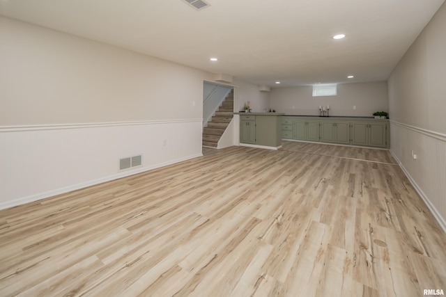 spare room featuring light wood-type flooring, visible vents, recessed lighting, and stairs