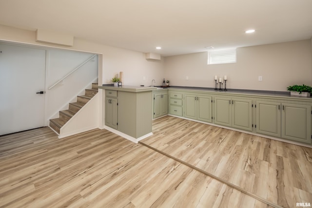 kitchen with light wood-type flooring, a peninsula, green cabinetry, and recessed lighting