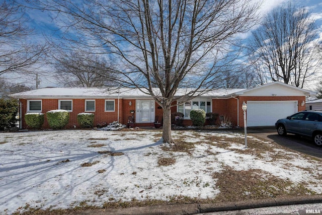 single story home featuring aphalt driveway, brick siding, and an attached garage