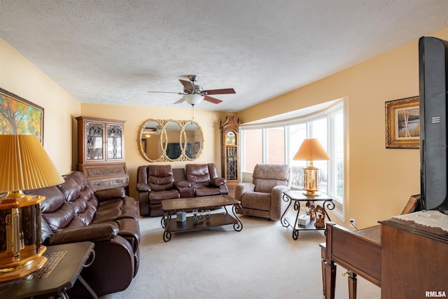 carpeted living room featuring ceiling fan and a textured ceiling