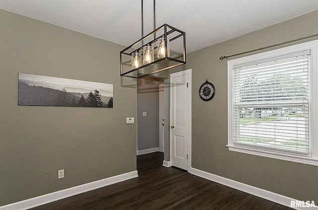 unfurnished dining area featuring baseboards and dark wood-type flooring