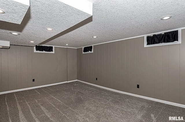 finished basement with a textured ceiling, dark colored carpet, recessed lighting, and baseboards