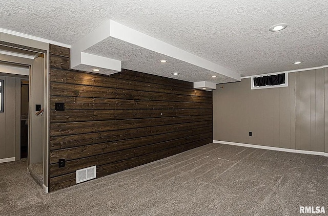 finished basement featuring wooden walls, baseboards, dark colored carpet, a textured ceiling, and recessed lighting