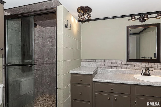 bathroom with a stall shower, backsplash, vanity, and toilet