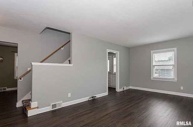 spare room with baseboards, stairs, visible vents, and dark wood finished floors