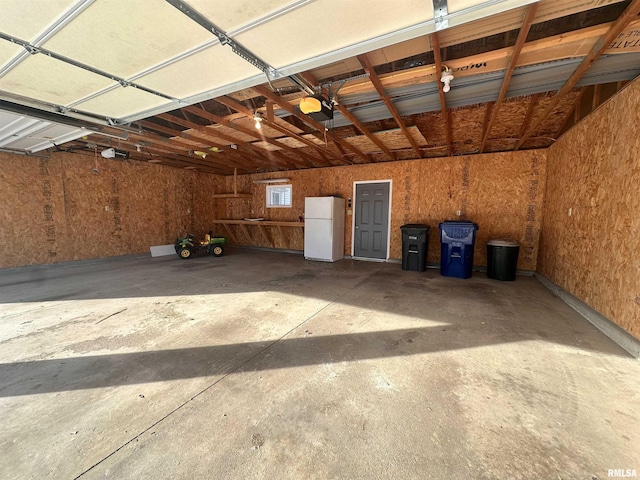 garage with a garage door opener and freestanding refrigerator