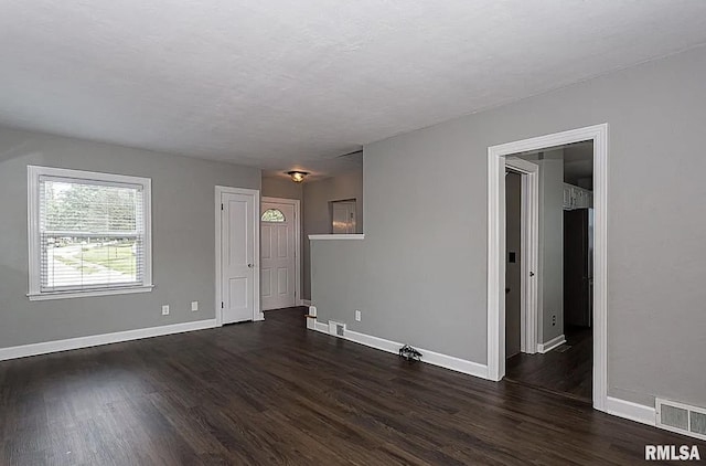 spare room featuring dark wood finished floors, visible vents, and baseboards