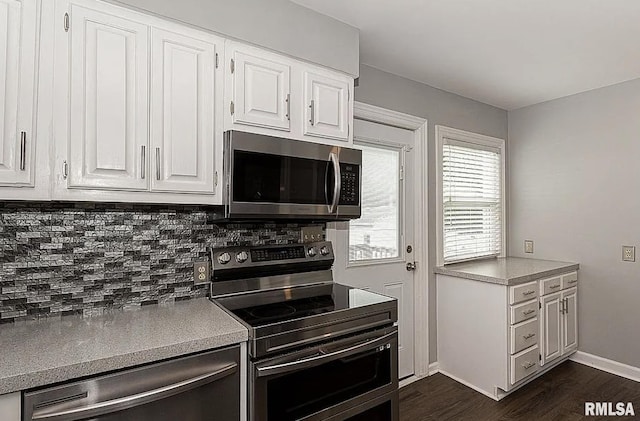 kitchen featuring dark wood finished floors, backsplash, appliances with stainless steel finishes, white cabinets, and baseboards