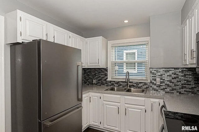 kitchen with a sink, white cabinets, light countertops, freestanding refrigerator, and tasteful backsplash