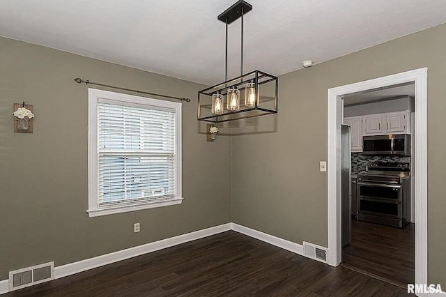 unfurnished dining area featuring baseboards, visible vents, and dark wood-type flooring