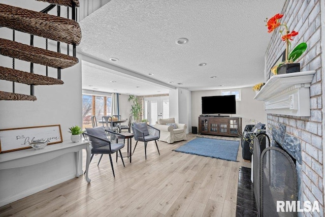 living area featuring a textured ceiling, a healthy amount of sunlight, a fireplace, and light wood finished floors