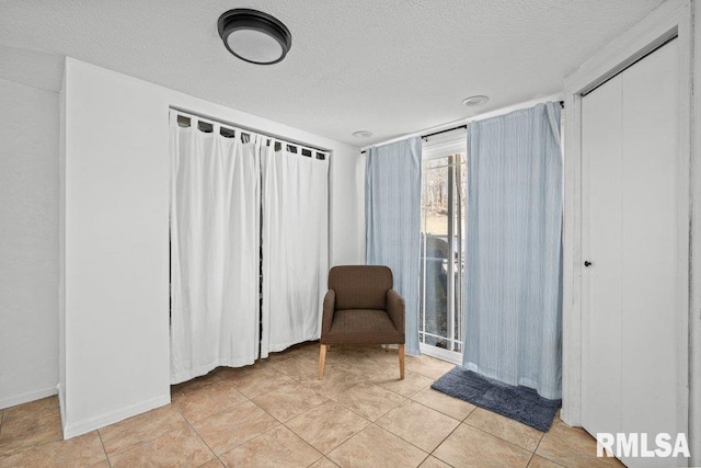 unfurnished room with light tile patterned floors, a textured ceiling, and baseboards