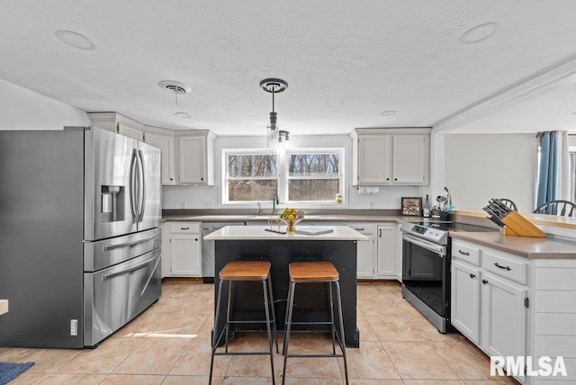 kitchen featuring visible vents, a peninsula, appliances with stainless steel finishes, a kitchen bar, and a center island