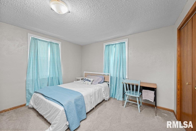 bedroom with light colored carpet, a textured ceiling, baseboards, and a textured wall