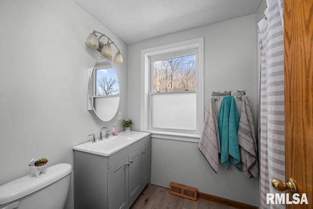 bathroom with vanity, wood finished floors, visible vents, baseboards, and toilet