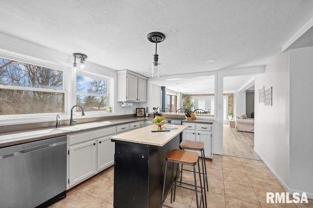 kitchen with a kitchen island, dishwasher, a peninsula, a kitchen breakfast bar, and a sink