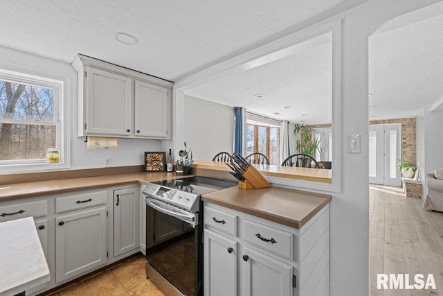 kitchen featuring plenty of natural light, range with electric stovetop, and a textured ceiling