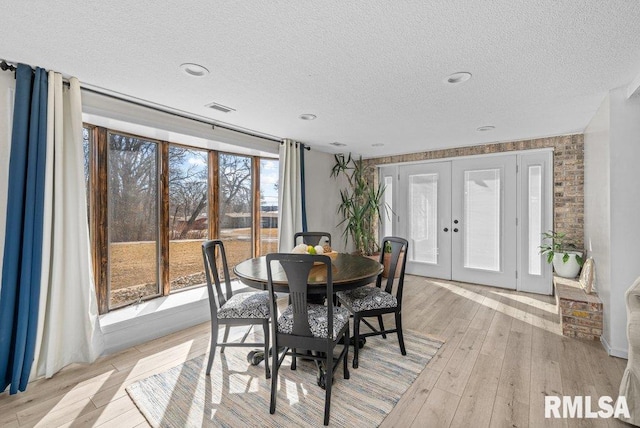 dining area featuring french doors, light wood-style floors, visible vents, and a textured ceiling