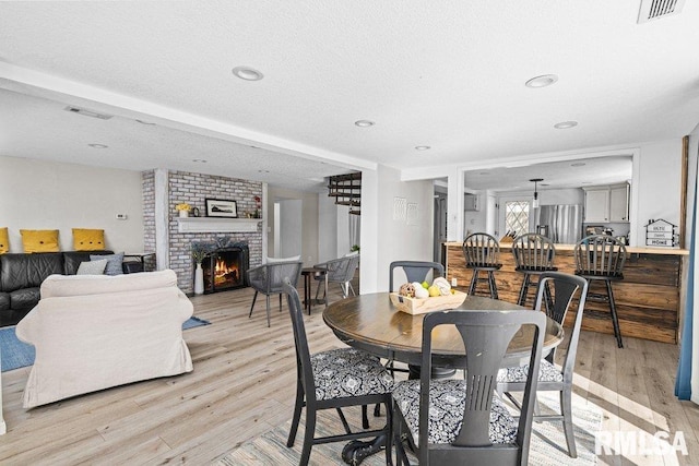 dining room with recessed lighting, a fireplace, visible vents, and light wood finished floors