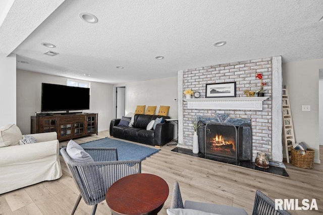 living area featuring visible vents, a brick fireplace, recessed lighting, wood finished floors, and a textured ceiling