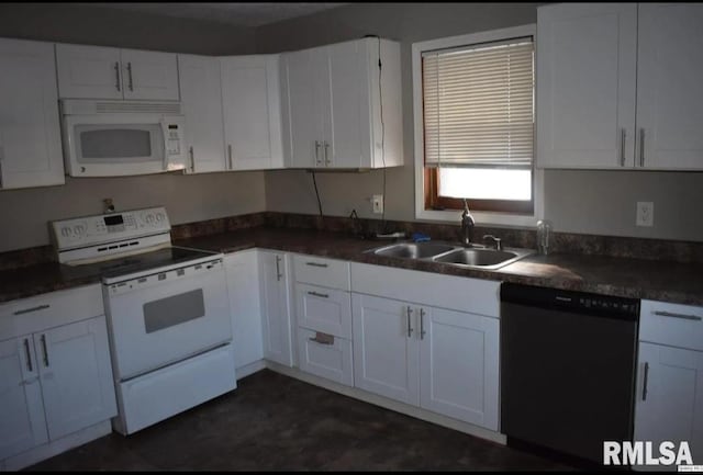 kitchen featuring dark countertops, white appliances, white cabinetry, and a sink