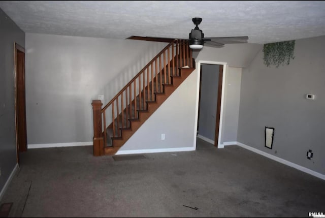 unfurnished living room with a ceiling fan, dark carpet, baseboards, and stairs