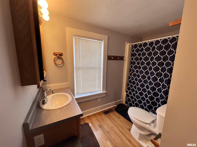 bathroom featuring curtained shower, toilet, vanity, wood finished floors, and baseboards