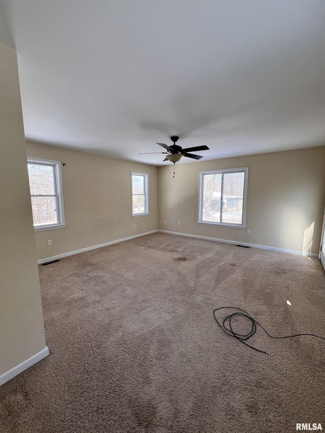 spare room featuring carpet floors, ceiling fan, visible vents, and baseboards