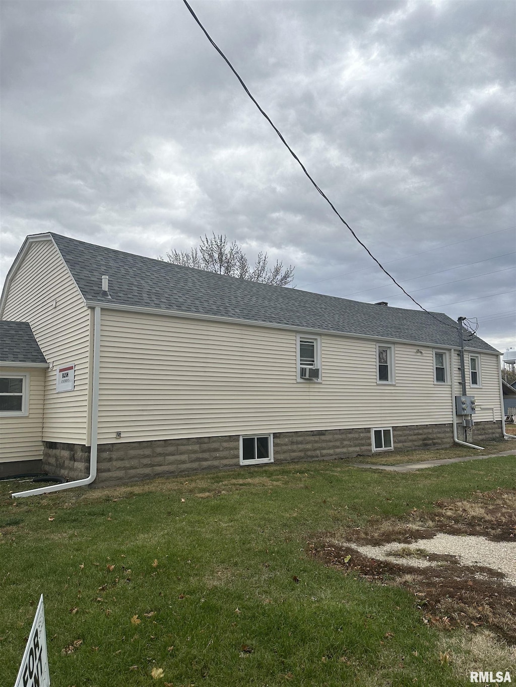 view of side of home with a yard and a shingled roof