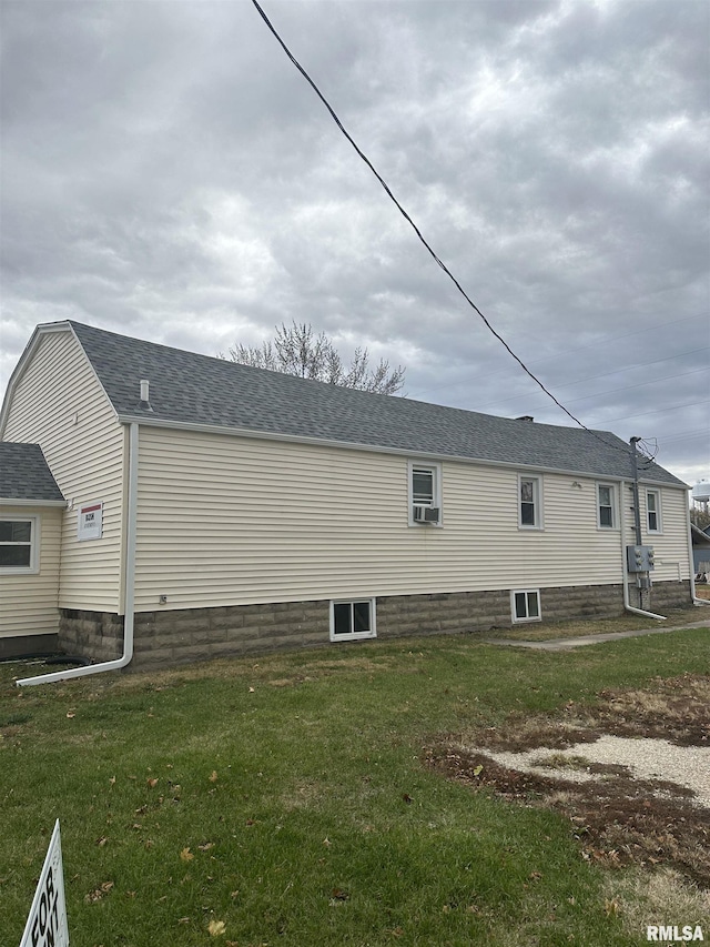 view of side of home with a yard and a shingled roof