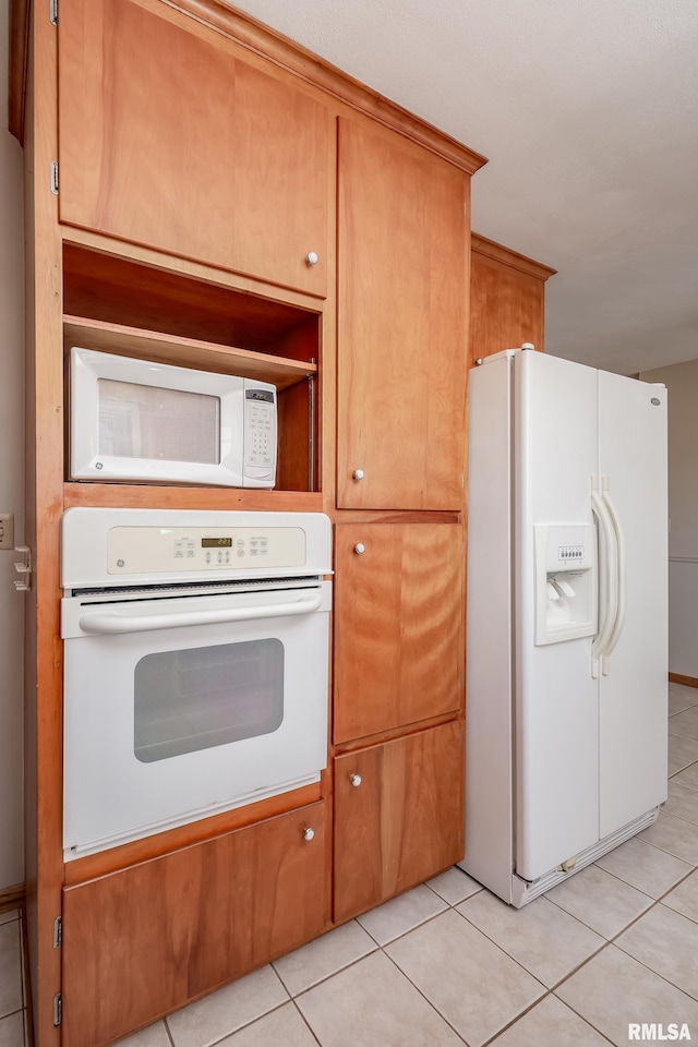 kitchen featuring brown cabinetry, white appliances, and light tile patterned flooring