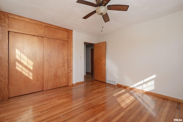 unfurnished bedroom with a ceiling fan, baseboards, visible vents, light wood-style floors, and a closet