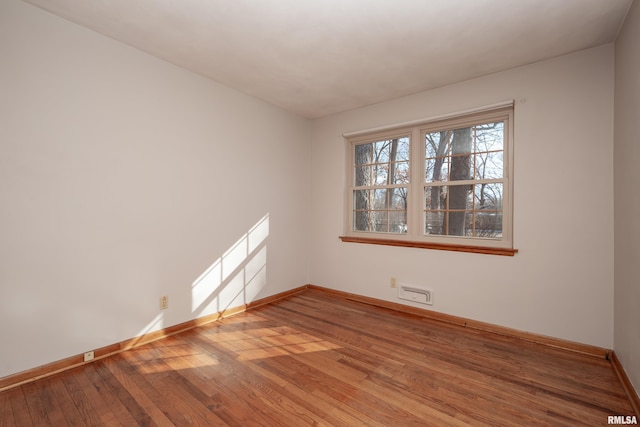 spare room with hardwood / wood-style floors and baseboards