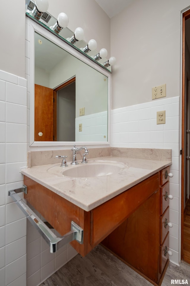 bathroom with a wainscoted wall, wood finished floors, tile walls, and vanity