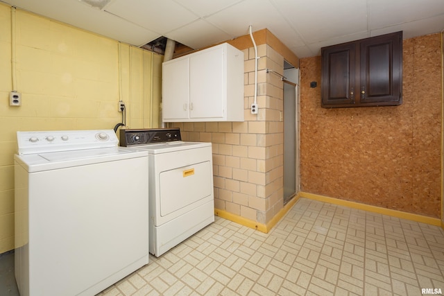 clothes washing area featuring cabinet space, baseboards, and washer and dryer